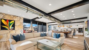 A modern living room with a sectional sofa, a coffee table, and a stone accent wall. - Sleeps 10 in Jax Beach - 2BR/2BA - Pool Table + Firepit (Jacksonville Beach)