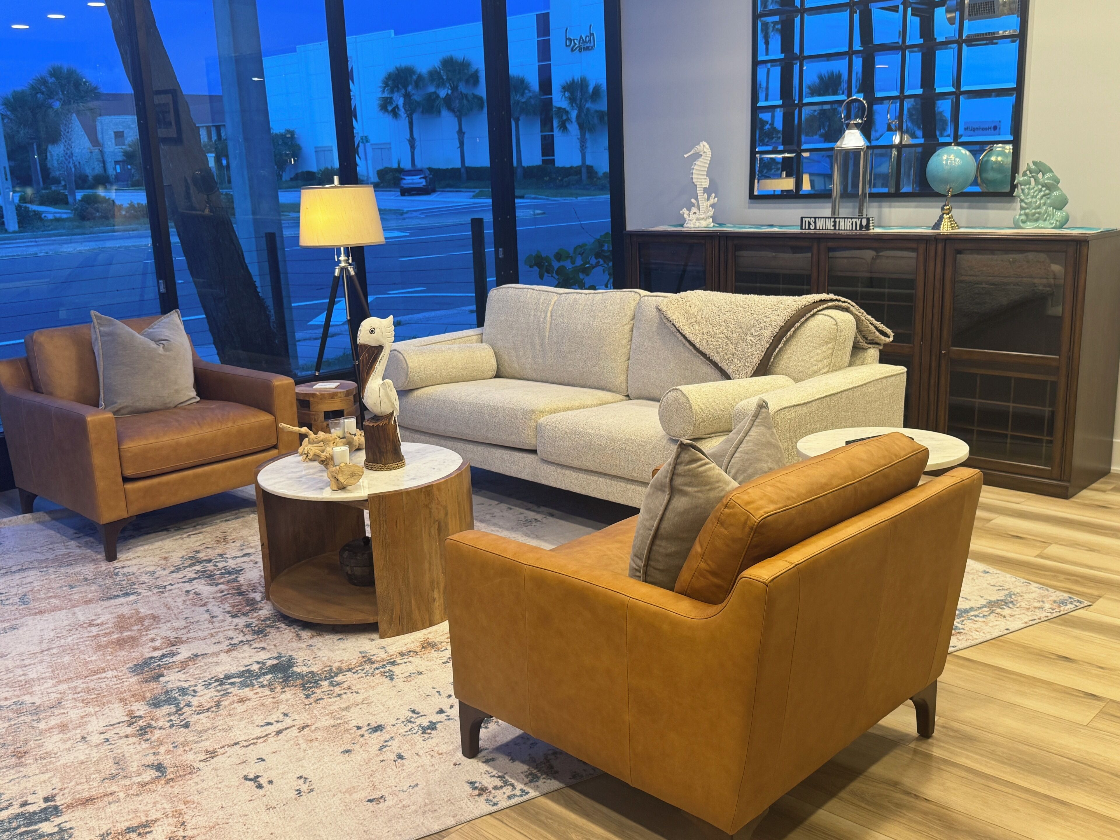 A living room with a sofa, armchair, coffee table, lamp, and decorative items.
