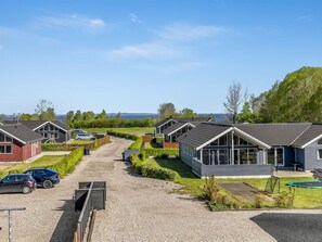 Eine Reihe moderner, eingeschossiger Häuser mit Kiesauffahrt und freiem Blick auf das Meer im Hintergrund.