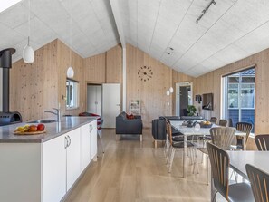 Eine moderne Küche mit Holzvertäfelung, einer großen Uhr und einem Essbereich mit Stühlen und einem Tisch.