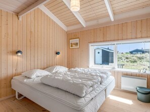 Ein Zimmer mit Holzwänden, einem Bett, einem Fenster mit Blick und einer Heizung.