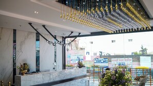 Zona de recepción con mostrador de mármol, elementos decorativos colgantes y vistas al exterior.