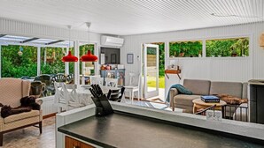 Eine moderne Küche mit einer zentralen Kochinsel, weißen Schränken und einem Essbereich mit Tisch und Stühlen.