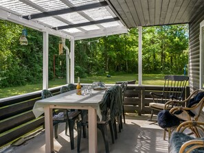 An outdoor patio with a table and chairs, a pergola with string lights, and a view of a green landscape. - "Erk" -  from the sea by Interhome (Hadsund)