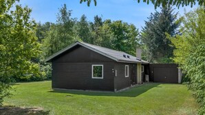 Ein eingeschossiges Gebäude mit Satteldach, einer kleinen angebauten Garage und einem gepflegten Rasen.