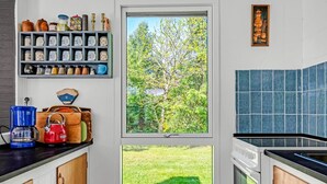 Eine Küche mit Fenster, einer Kaffeemaschine, einem Wasserkocher und einem Regal mit Küchenutensilien.