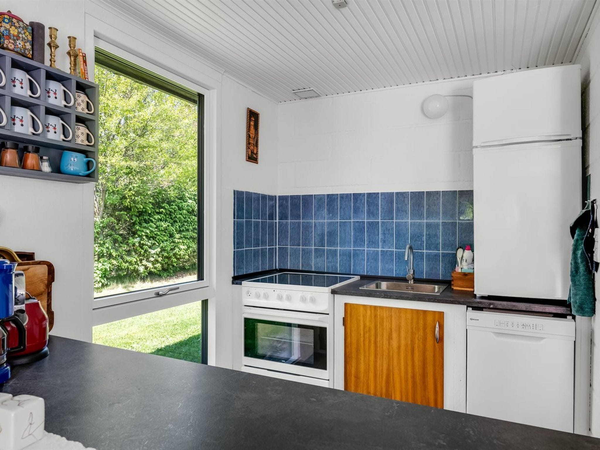 Eine moderne Küche mit Fenster, Herd, Spüle und Kühlschrank.