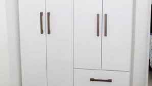 Ein weißer Kleiderschrank mit zwei Türen und zwei Schubladen, mit Metallgriffen.
