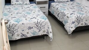 Ein Schlafzimmer mit zwei Betten, jeweils mit passender Kopfstütze und Kissen, einem kleinen Nachttisch und einer Wandsticker.