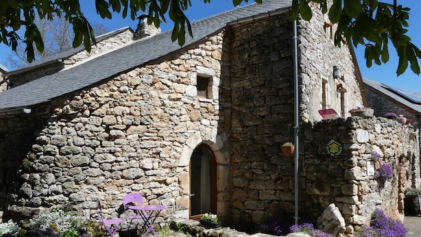 A stone building with a wooden door, a small window, and a sign indicating a restaurant.