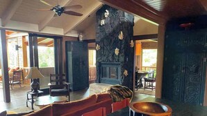 A spacious living area with a fireplace, a dining table, and a seating area with red chairs. - Cloud 9, Hawaiian  Forest Retreat
Get away from it all, but close to everything. (Kailua-Kona)