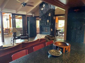 A spacious living area with a fireplace, a dining table, and a seating area with red chairs. - Cloud 9, Hawaiian  Forest Retreat
Get away from it all, but close to everything. (Kailua-Kona)
