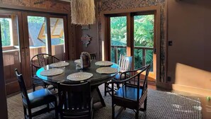 A dining area with a round table, chairs, and a hanging light fixture. - Cloud 9, Hawaiian  Forest Retreat
Get away from it all, but close to everything. (Kailua-Kona)
