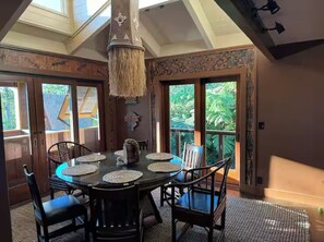 A dining area with a round table, chairs, and a hanging light fixture. - Cloud 9, Hawaiian  Forest Retreat
Get away from it all, but close to everything. (Kailua-Kona)