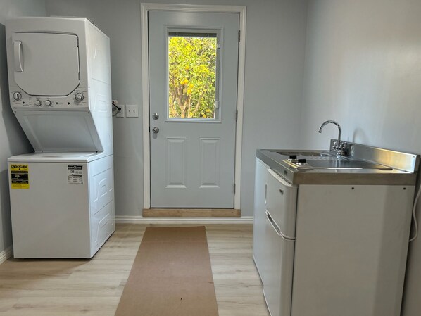 A compact kitchen with a washing machine, a sink, and a door leading to a garden. - Secret garden in center of LA, 3mi Sofi, 4 mi LAX, 6 mi beach, pets welcome (Los Angeles)
