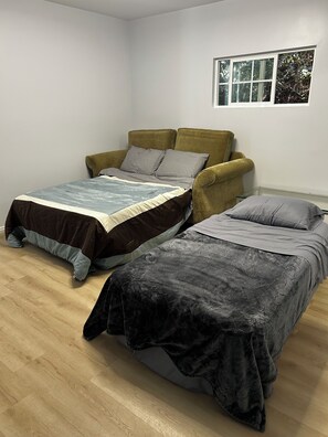 A room with two beds, a sofa, and a window. - Secret garden in center of LA, 3mi Sofi, 4 mi LAX, 6 mi beach, pets welcome (Los Angeles)