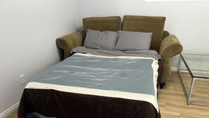 A bed with a grey and white duvet, a brown sofa with grey cushions, and a glass coffee table. - Secret garden in center of LA, 3mi Sofi, 4 mi LAX, 6 mi beach, pets welcome (Los Angeles)