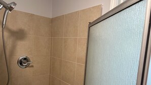 A shower area with beige tiles, a showerhead, and a glass door. - Secret garden in center of LA, 3mi Sofi, 4 mi LAX, 6 mi beach, pets welcome (Los Angeles)