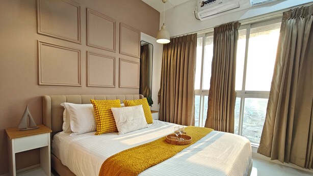 A hotel room with a bed, nightstand, air conditioning unit, and large windows with curtains. - Terrific 2-bedroom apartment with AC in vibrant Mumbai (Mumbai)