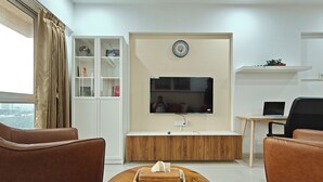 A modern living room with a TV, sofa, and a small table with a tissue box. - Terrific 2-bedroom apartment with AC in vibrant Mumbai (Mumbai)
