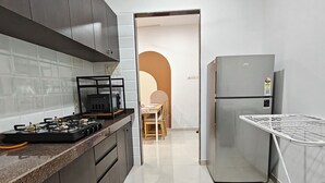 A modern kitchen with dark cabinets, a gas stove, a refrigerator, and a drying rack. - Terrific 2-bedroom apartment with AC in vibrant Mumbai (Mumbai)