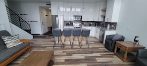 Eine moderne Küche mit weißen Schränken, einem Edelstahlkühlschrank und einem Essbereich mit Holztisch und -stühlen.