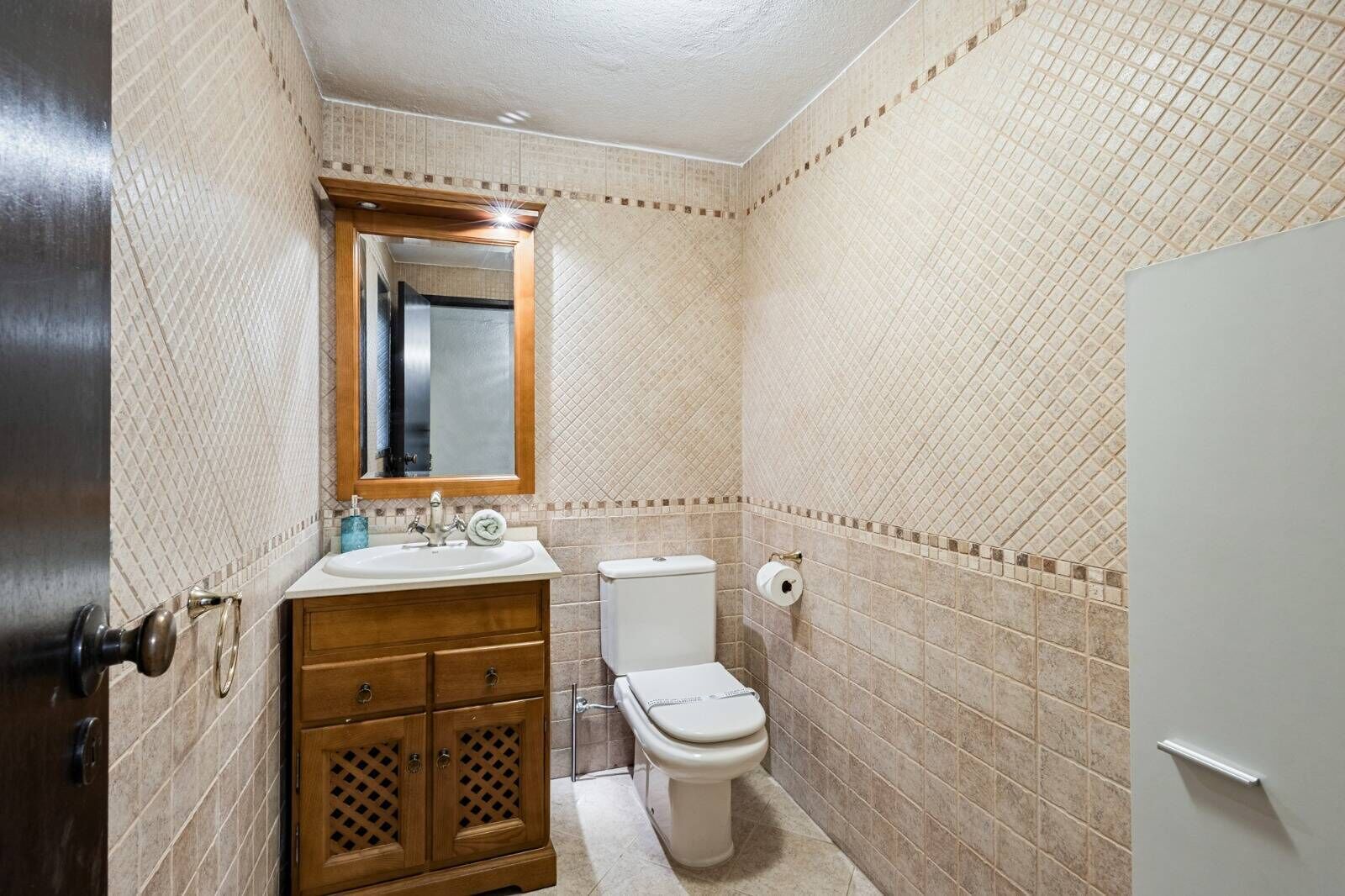 Une salle de bain avec un meuble-lavabo en bois, des toilettes et un miroir au-dessus du lavabo.