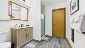 Ein Badezimmer mit einem Holzkosmetikschrank, einem Spiegel, einem Waschbecken und einer Toilette.