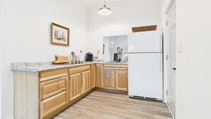 Eine Küche mit Holzausstattung, einem weißen Kühlschrank, einer Granitarbeitsplatte und einer Pendelleuchte.