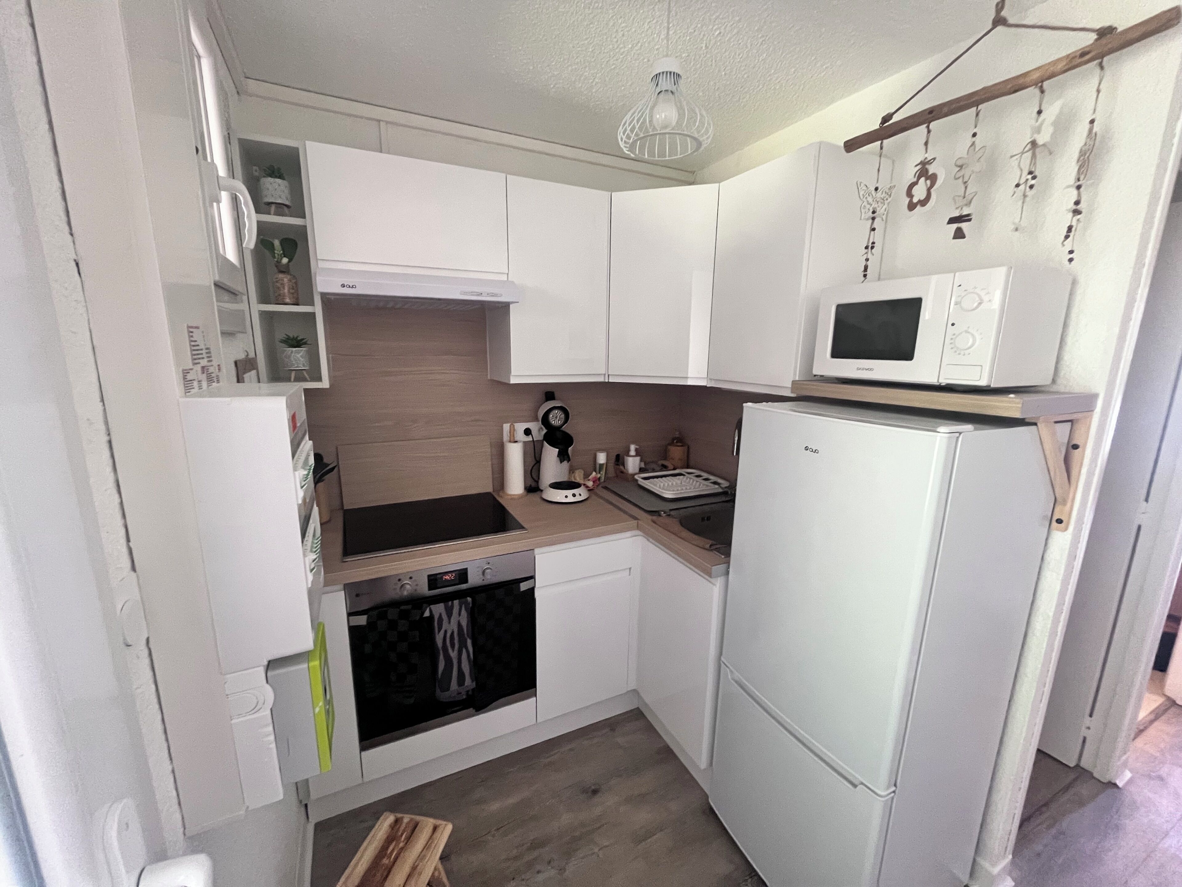 Una cocina compacta con armarios blancos, un microondas, una estufa y un horno pequeño.