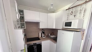 Eine kompakte Küche mit weißen Schränken, einer Mikrowelle, einem Herd und einem kleinen Backofen.