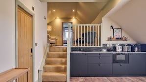 A modern kitchen with dark cabinetry, a built-in oven, and a coffee station. - Grain Loft - Luxury Cottages (Caersws)