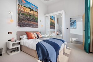 Un dormitorio moderno con una cama grande, un cuadro, una escalera y vistas al exterior.