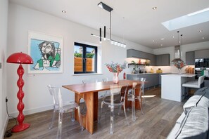 Una cocina moderna con armarios grises, una mesa de comedor de madera y sillas transparentes.