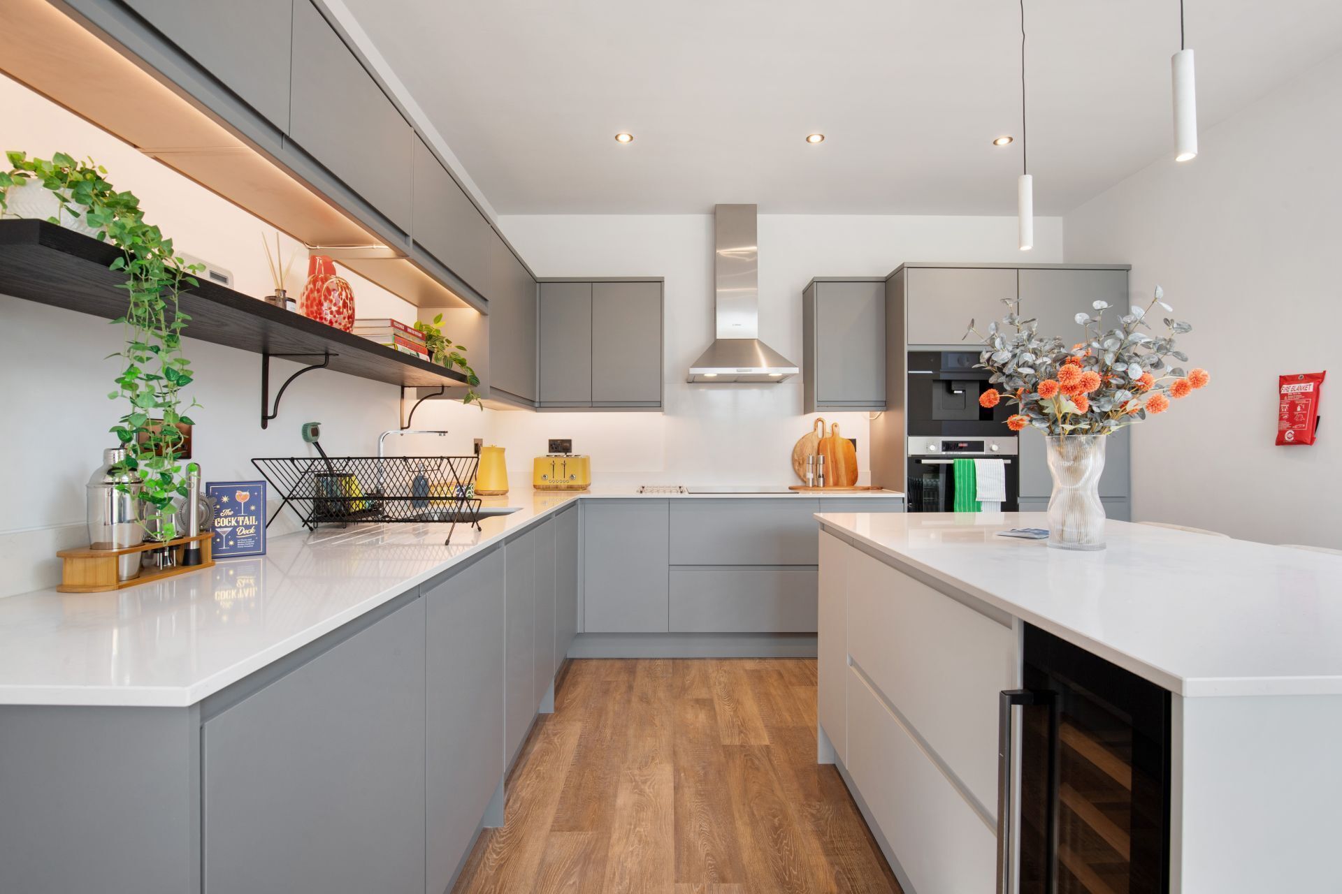 Une cuisine moderne avec des meubles de couleur grise, un plan de travail en bois et un îlot central.