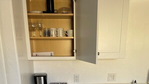 A compact kitchen with a washing machine, a coffee maker, a toaster, and a cabinet with glassware. - Puppy play pen 2-bedroom house with AC in sunny Phoenix (Phoenix)
