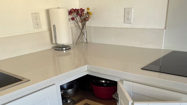 A corner kitchen with white cabinets, a stainless steel sink, and a vase with flowers on the countertop. - Puppy play pen 2-bedroom house with AC in sunny Phoenix (Phoenix)