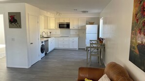 A modern kitchen with white cabinets, a microwave, and a refrigerator. There is a dining area with a table and chairs. - Puppy play pen 2-bedroom house with AC in sunny Phoenix (Phoenix)