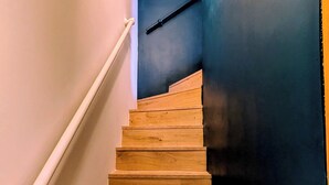 Eine Holzt Treppe mit Handlauf, die zu einer dunklen Wand führt.
