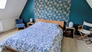 Ein Schlafzimmer mit Bett, Stuhl, Nachttisch und Fenster.