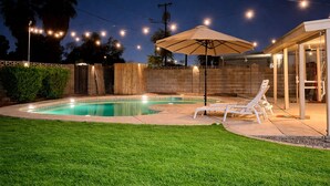 A backyard with a swimming pool, a covered patio area, and a lawn. - 3-bedroom house in pleasant Phoenix with Pool AC and comfort (Phoenix)