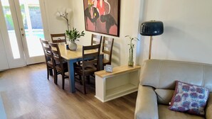 A dining area with a table and chairs, a vase with plants, a painting on the wall, a lamp, and a sofa with a cushion. - 3-bedroom house in pleasant Phoenix with Pool AC and comfort (Phoenix)