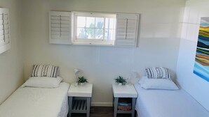 A room with two beds, a window with shutters, a ceiling fan, and a small table with a plant. - 3-bedroom house in pleasant Phoenix with Pool AC and comfort (Phoenix)