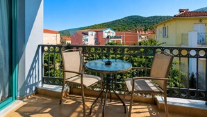 A balcony with a table and chairs, a view of buildings, and a mountain in the background. - Cleo Apartment - Quaint Loft in Kefalonia (Kefalonia)