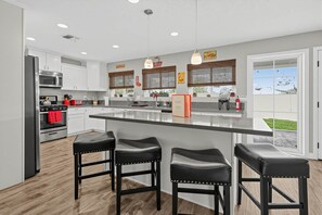 Una cocina moderna con armarios blancos, electrodomésticos de acero inoxidable y una isla grande con taburetes de bar.