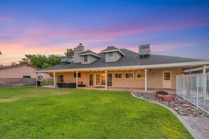 A residential house with a covered patio area, a fenced backyard, and a well-maintained lawn. - A wonderful Las Vegas Home. Close to the Action Sleeps 12 (Paradise)