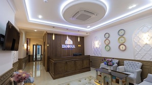 A lobby with a reception desk, seating area, decorative wall clocks, and a chandelier. - Boutique Hotel IMONA (Samarkand)