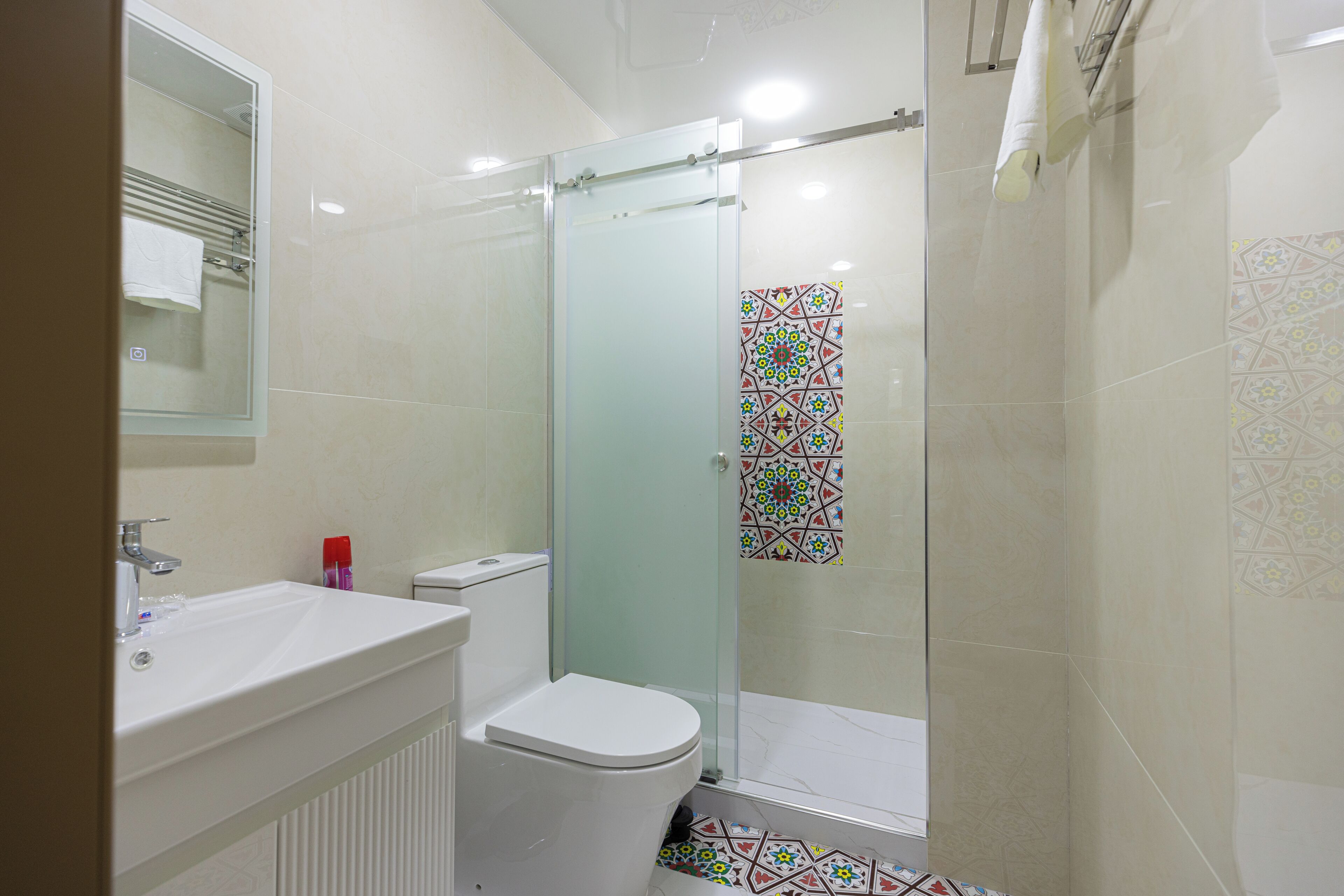 Une salle de bain avec une douche à parois de verre, un lavabo blanc et des toilettes.