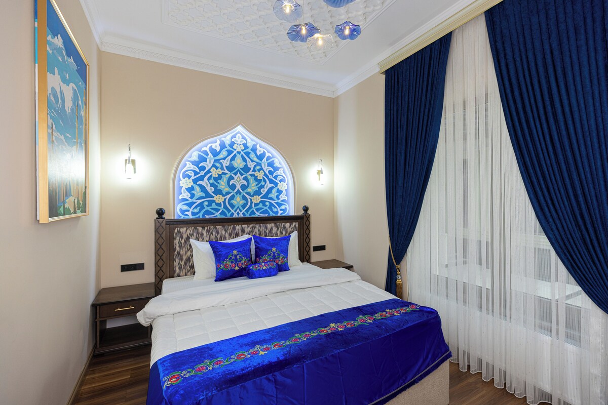 Une chambre d’hôtel avec un lit, une décoration murale, une table de chevet et une fenêtre avec des rideaux.