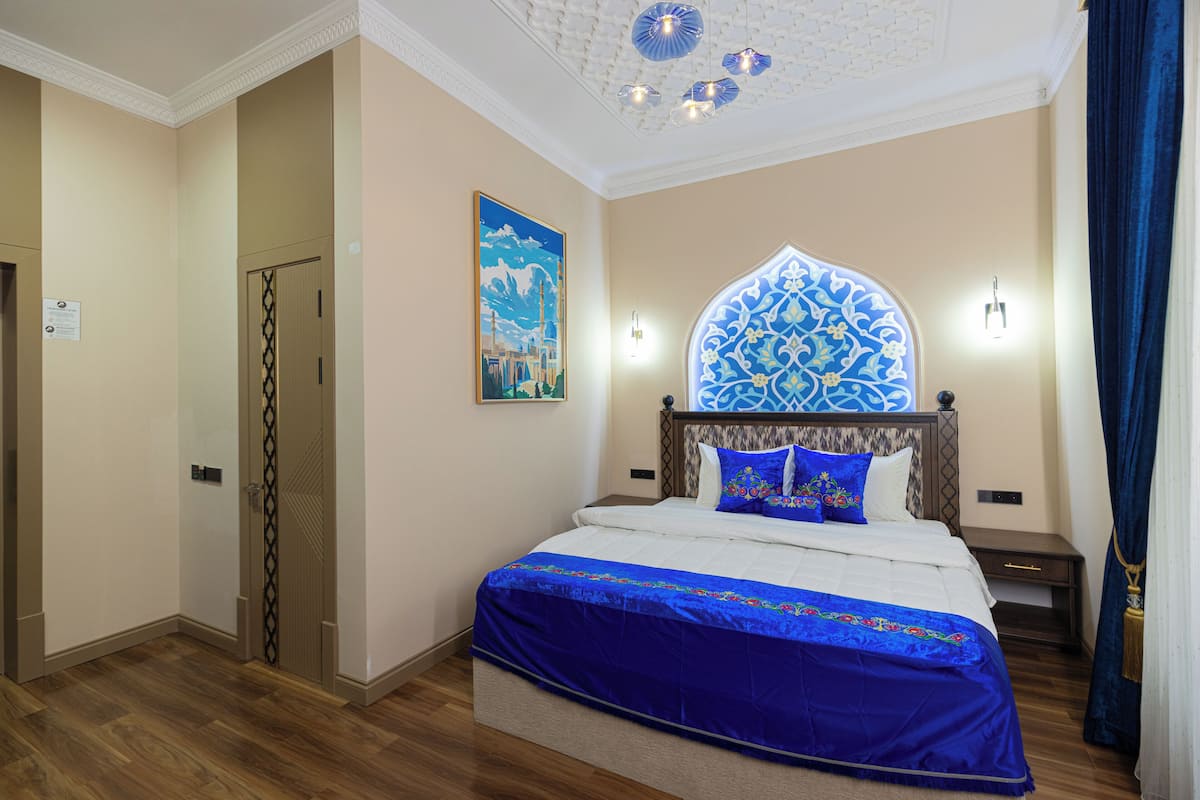 Une chambre à coucher avec un lit, une table de chevet, une lampe fixée au mur et une porte.